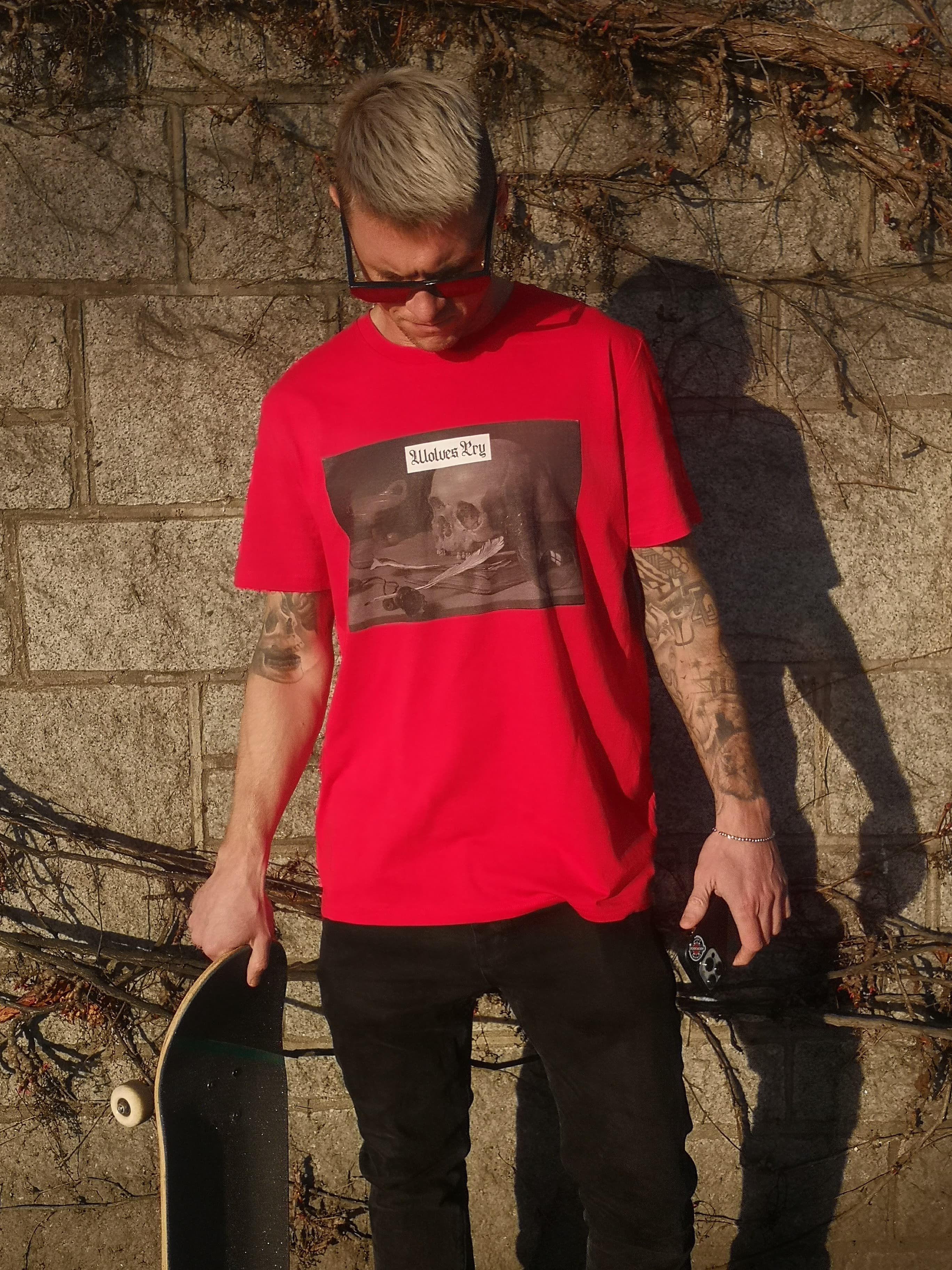 Model wearing the Wolves Cry Red Skull Tee in an urban setting, showcasing its striking color contrast and relaxed fit for effortless streetwear style.