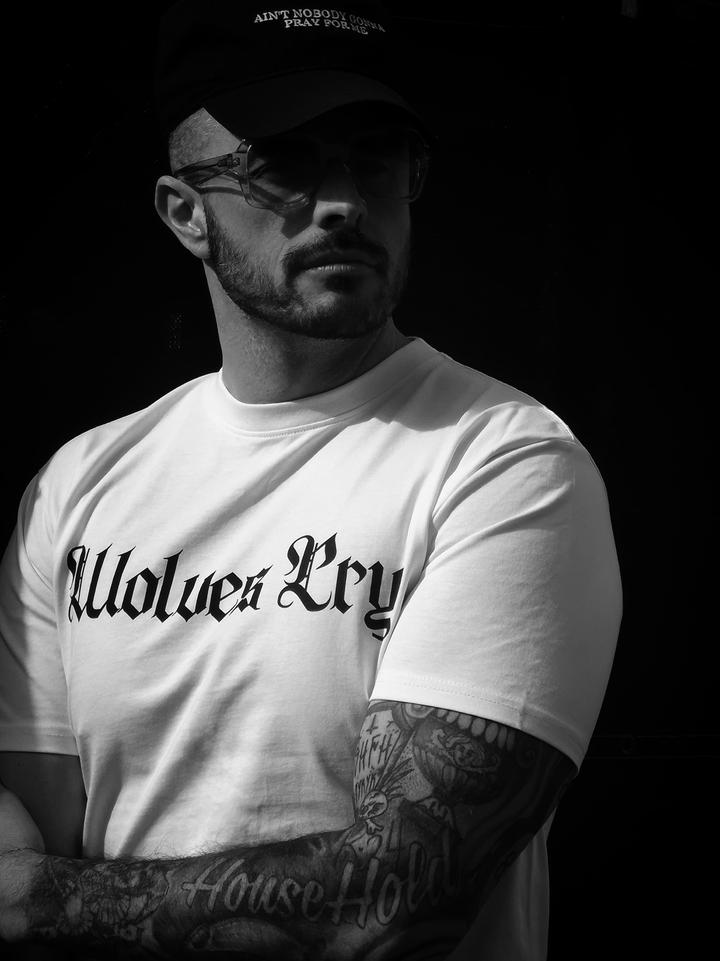 Male model wearing the Wolves Cry Spell-Out Tee in White, showcasing the relaxed fit and bold logo design. A classic streetwear piece built for everyday wear.